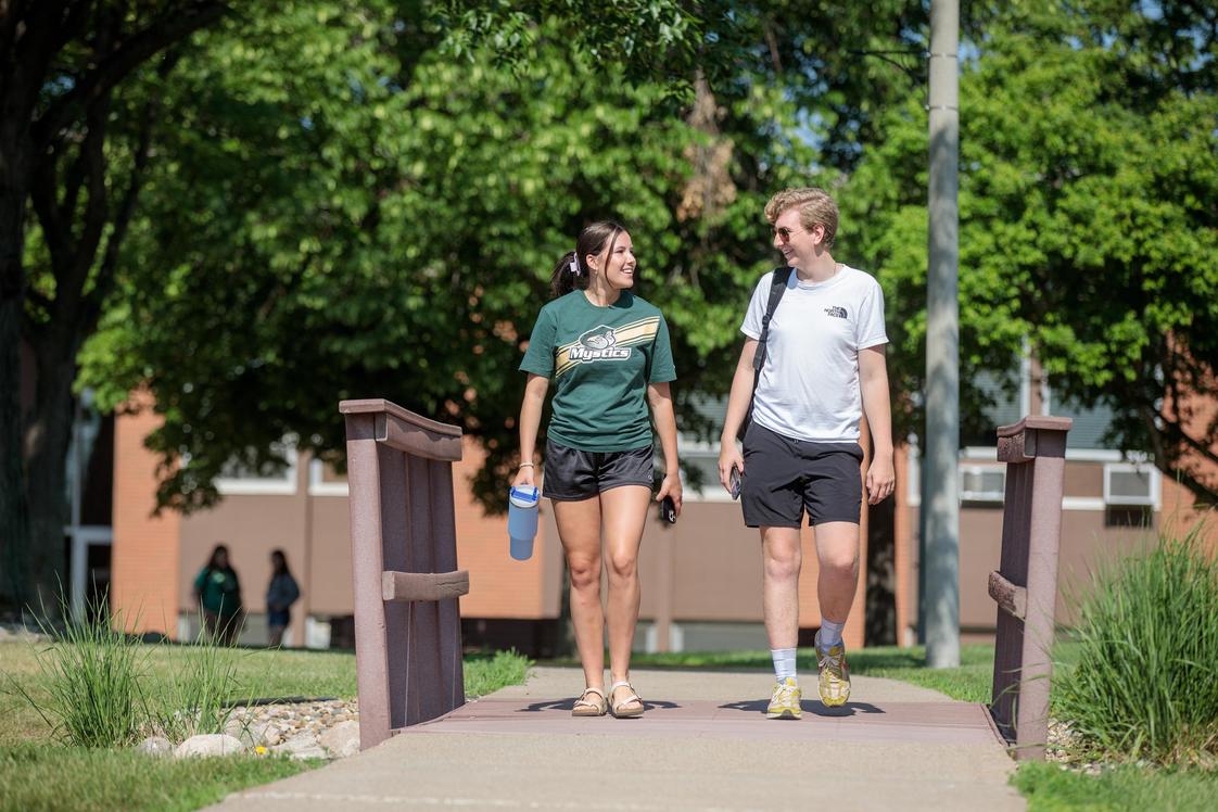 Bismarck State College Photo - Two students walking across the bridge near Schafer Hall, enjoying a beautiful day on Bismarck State College's vibrant campus-where connections are made, and futures are built.